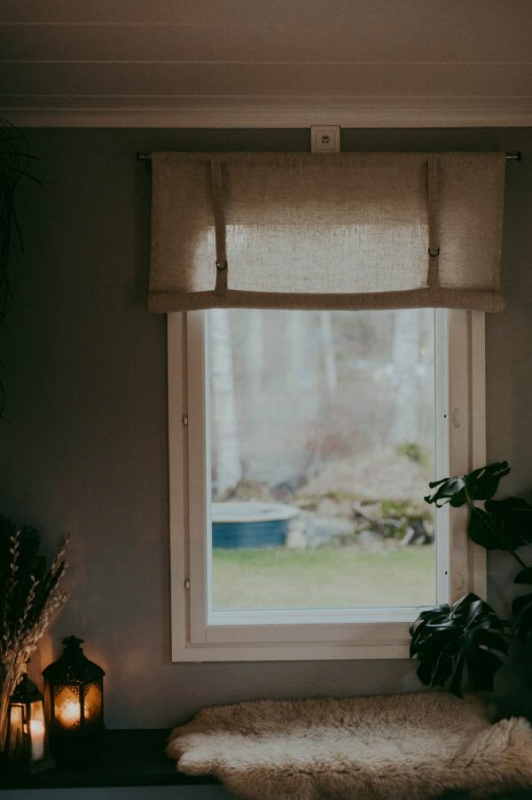 linnefärgad beige rullhissgardin i linne hänger i fönster.