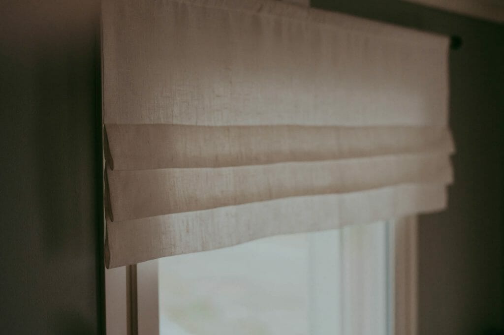 Linen faux roman curtain valance hanging in a window.