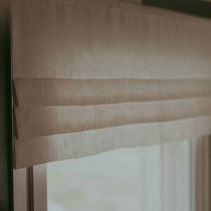 Linen faux roman curtain valance hanging in a window.