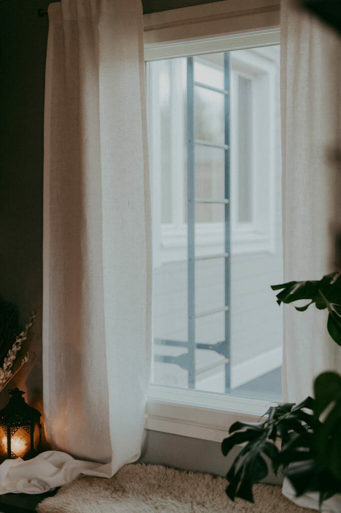 Ecological white Linen curtains hanging in cozy window.