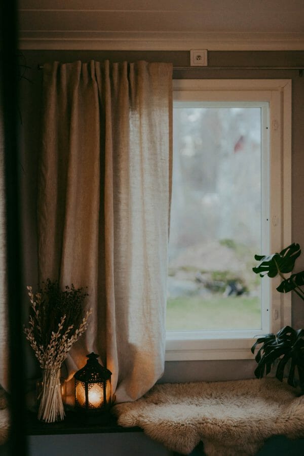 Ecological white Linen curtains hanging in cozy window.