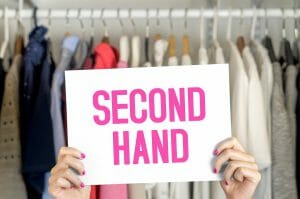 woman holding up sign with text 'second hand' in her wardrobe.